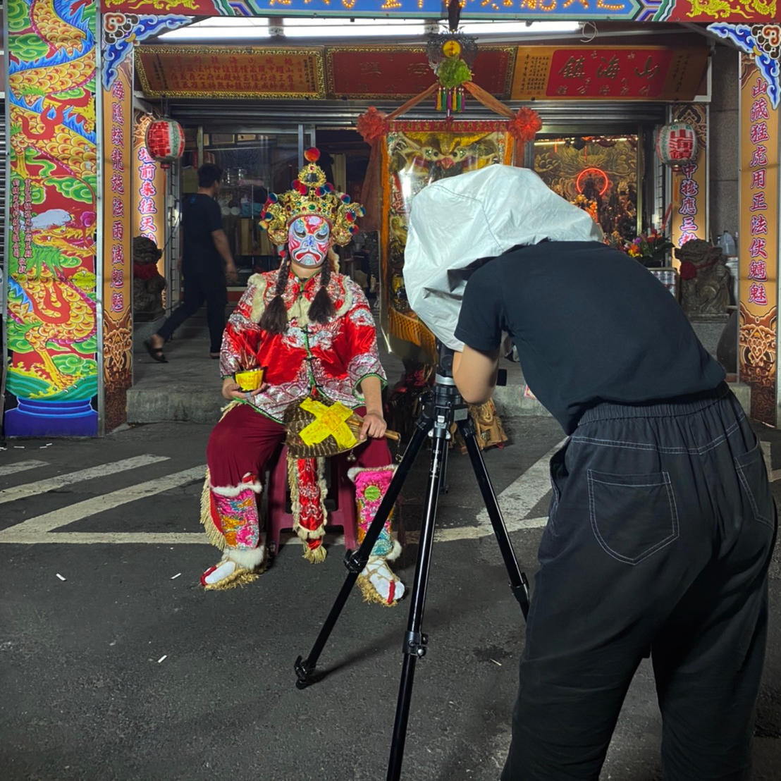 A person wearing all-black clothing taking an image of traditional Chinese culture