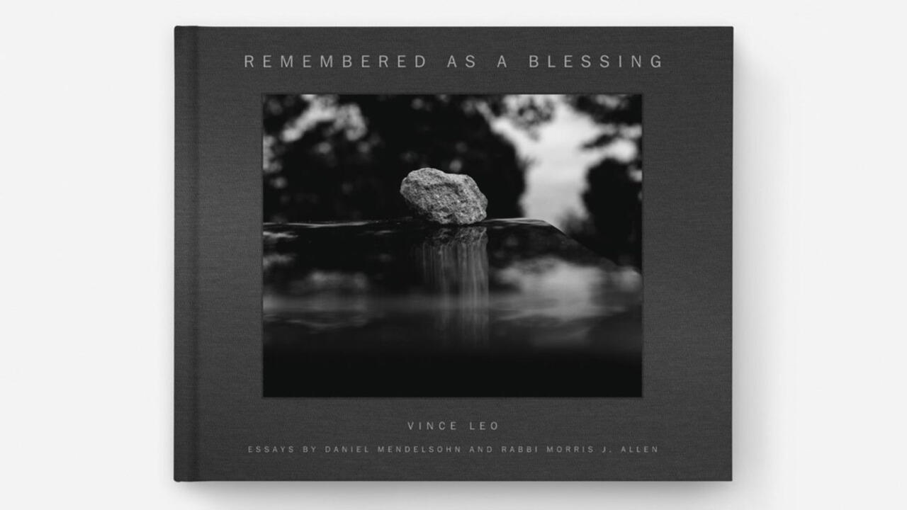 The cover of Remembered as a Blessing, it features a black and white color scheme and a rock in the middle of the photograph 