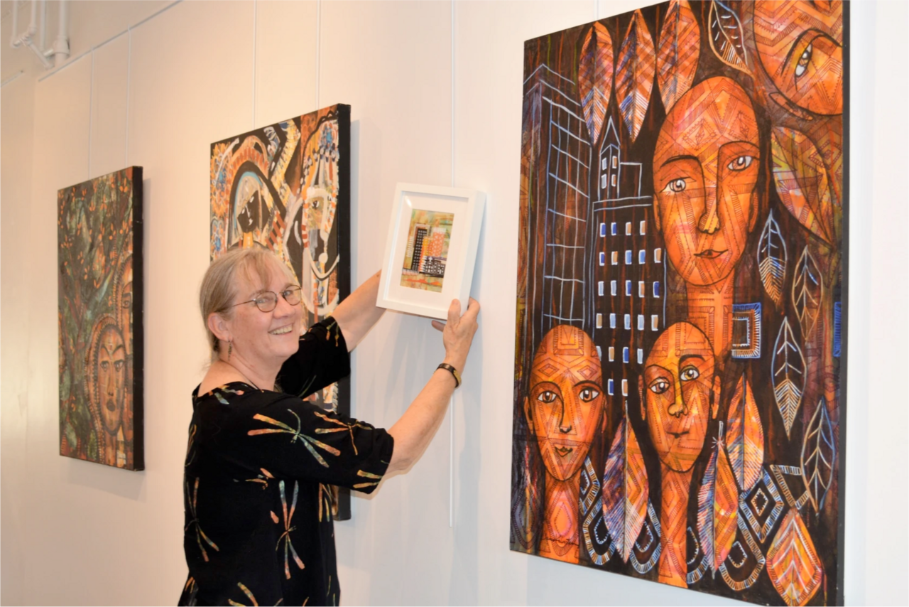 An image of Jamie Kalvestran hanging up her work at an exhibition.