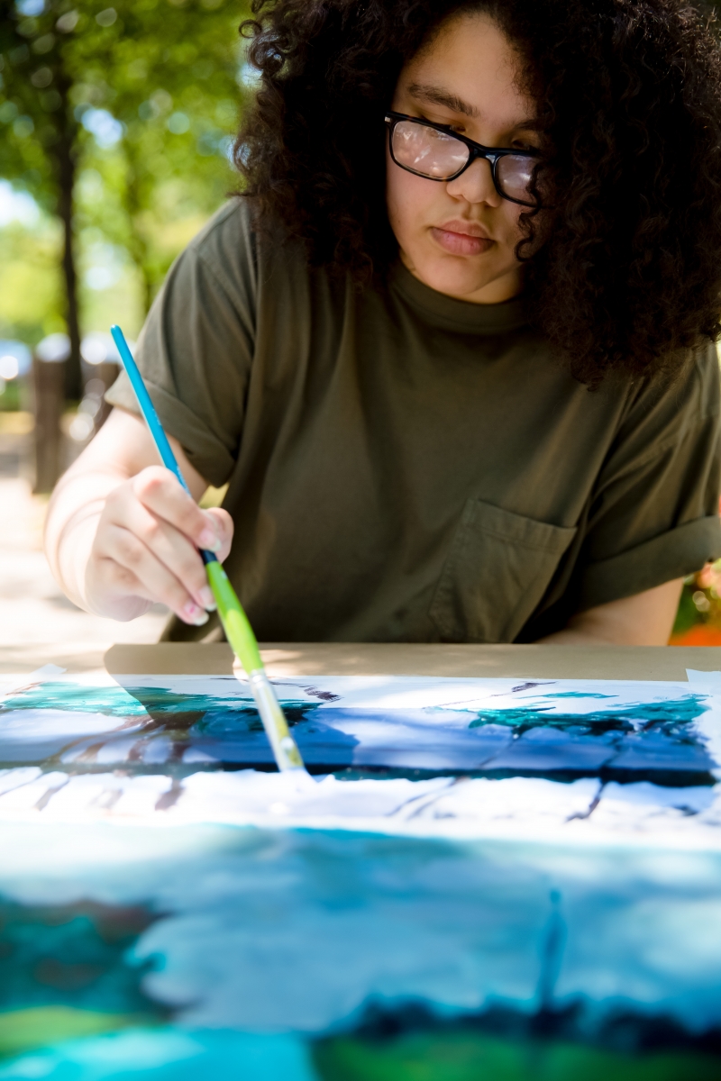 Imani works on one of her paintings outside. Photo by Grace Olson.