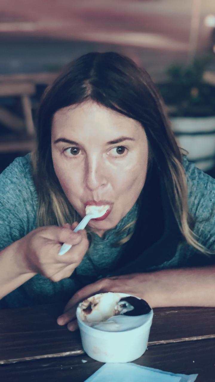 Portrait of Ashley Siebels. She is staring off into the distance while eating an ice cream sundae.