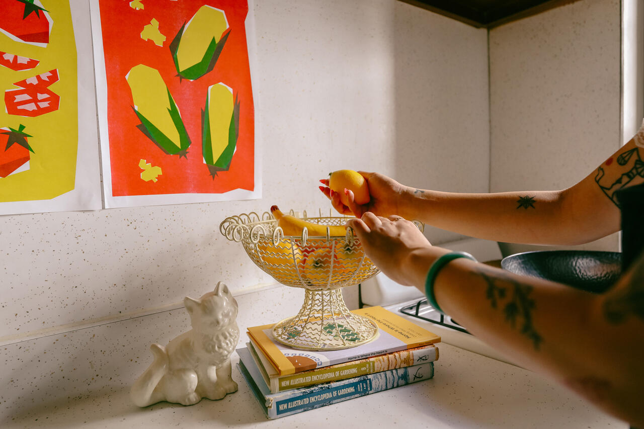 Student grabbing fruit out of a bowl on the kitchen counter