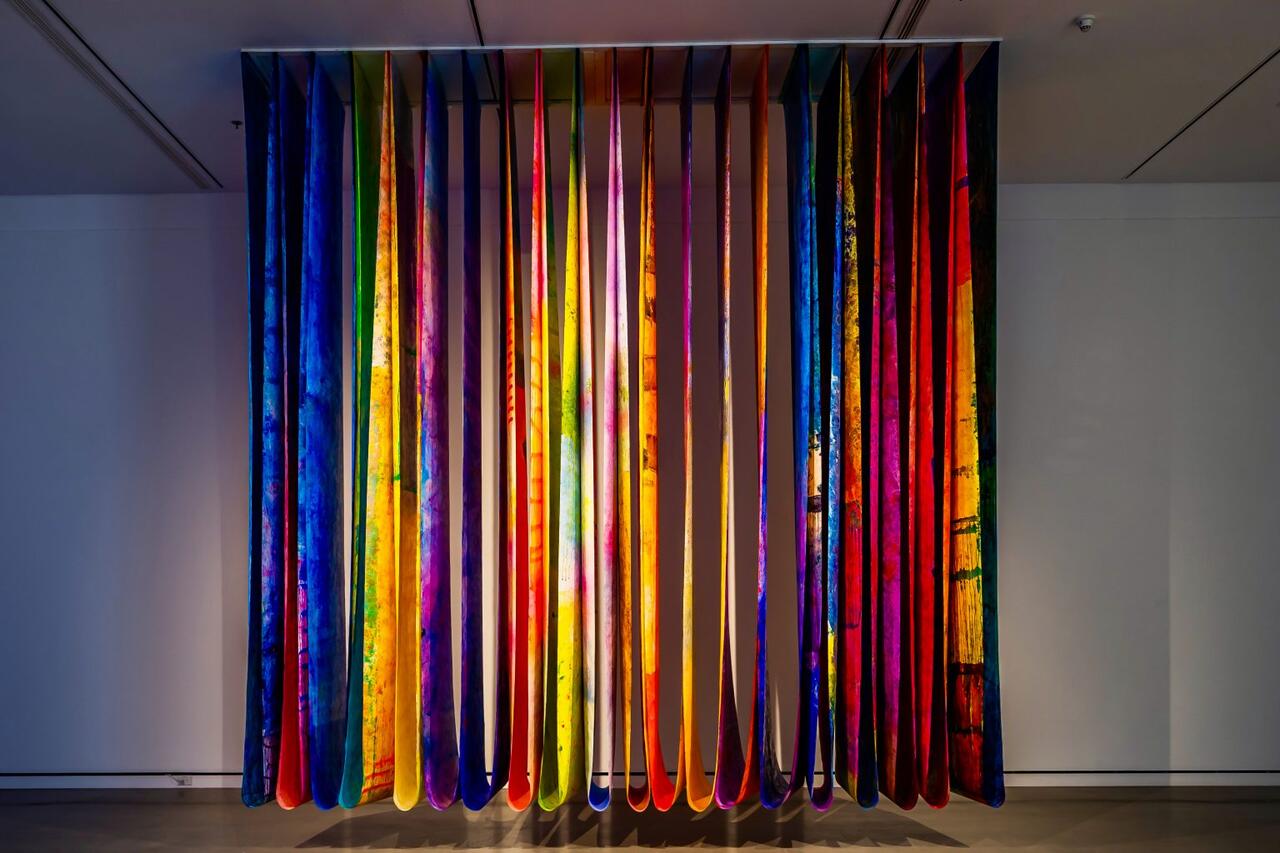 An image of a variously colored painted cloth hanging from the ceiling in an art gallery.