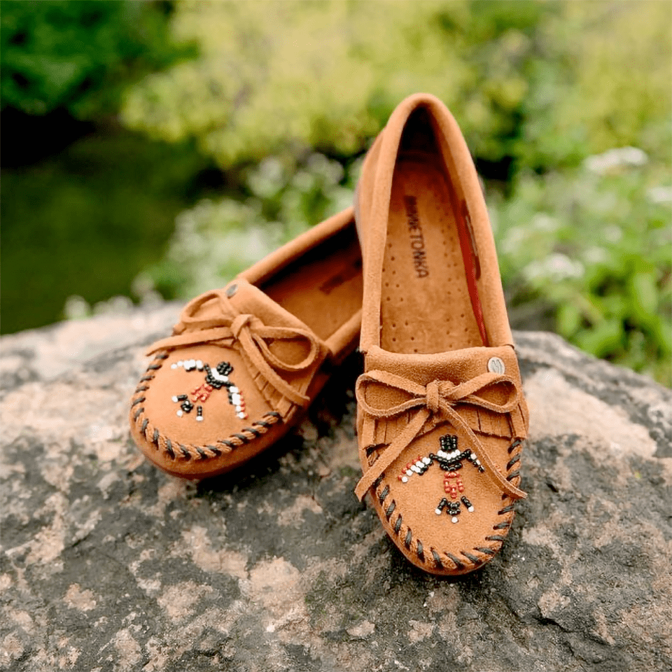 An image of moccasins being displayed on a rock in the woods.