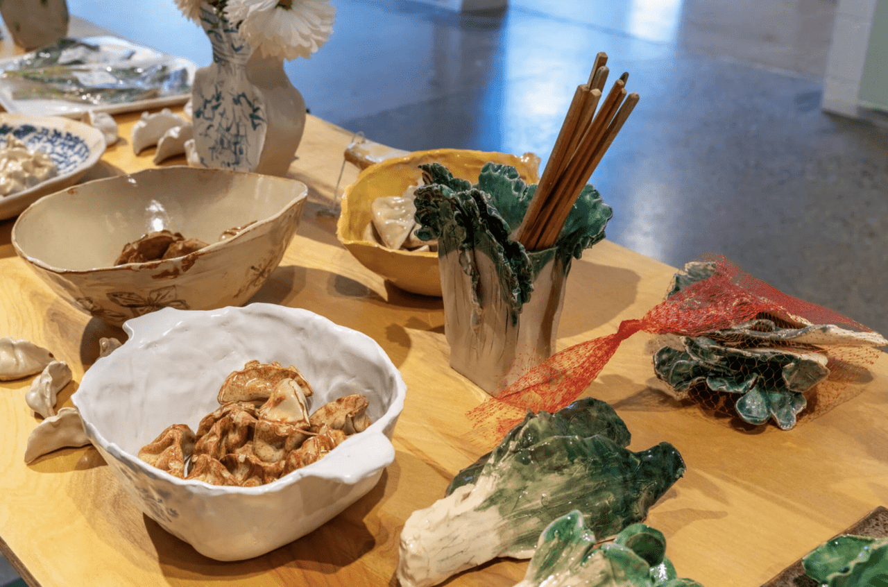 A photo of a wooden table with various cermaics. The ceramics depict east asian food in bowls, and the bowls have immitations of chinese designs and patterns.