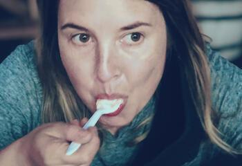 Portrait of Ashley Siebels. She is staring off into the distance while eating an ice cream sundae.