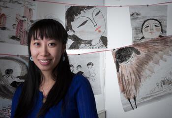 Wenwen sits in front of a collection of her paintings