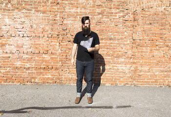 Portrait of Anthony Warnick, standing in front of a brick wall.