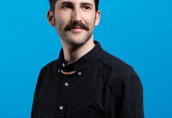 Portrait of Isaac Ruder against a blue background.